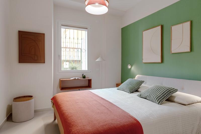 The Sage Room: double bed against a sage green wall, relief artworks and a window onto the street