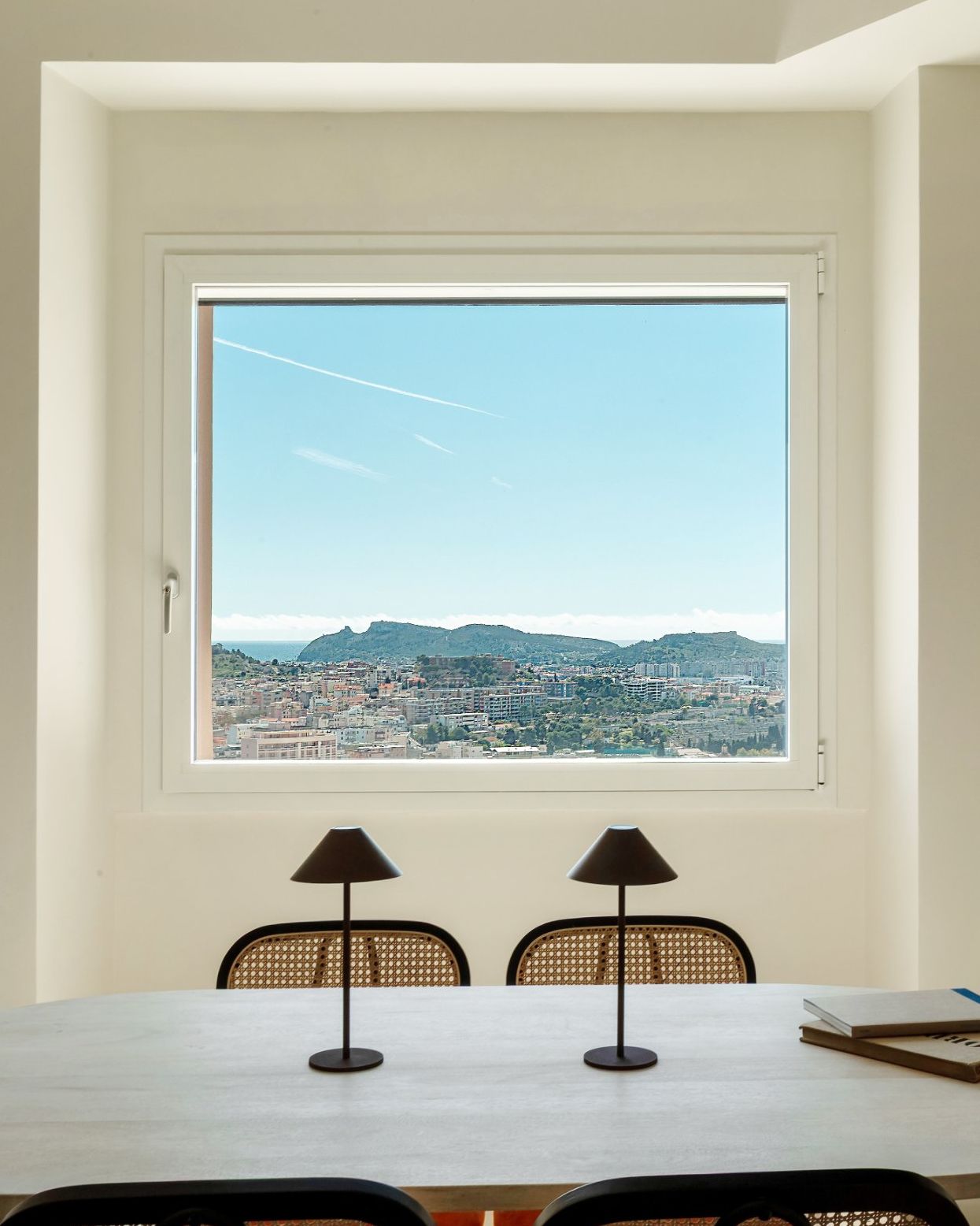 The dining table at Tàparas in front of a large window looking out over Cagliari to the Sella del Diavolo headland and the sea